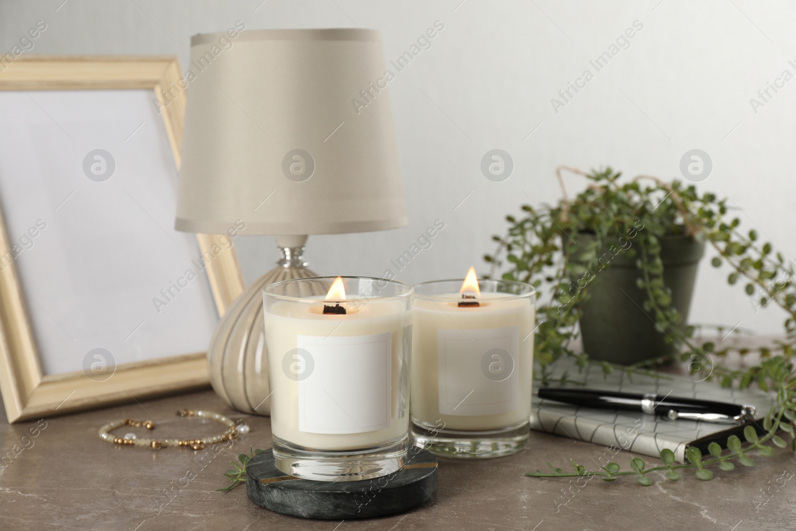 Photo of Burning soy candles with wooden wicks and decor on grey table