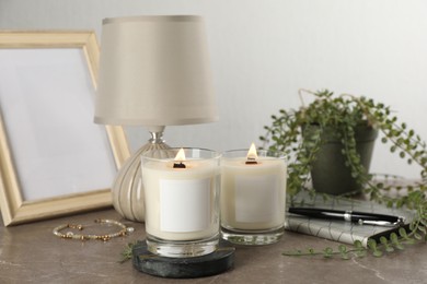 Burning soy candles with wooden wicks and decor on grey table