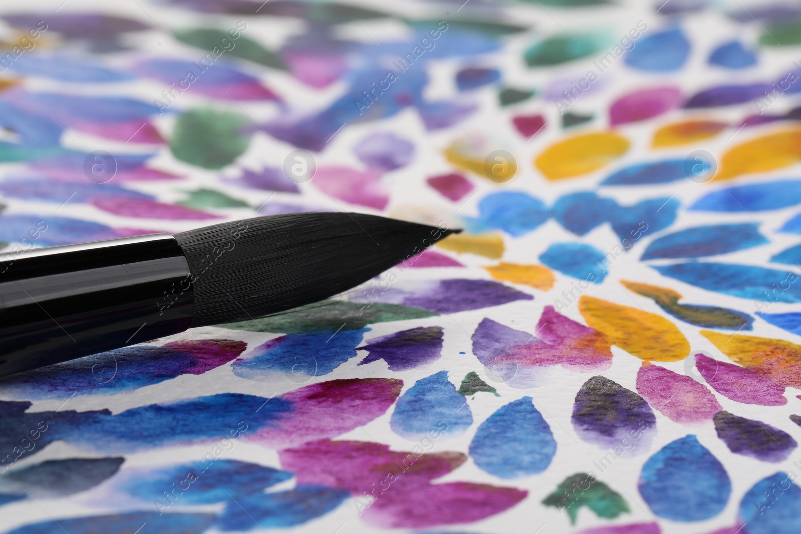 Photo of Closeup view of brush on abstract watercolor painting