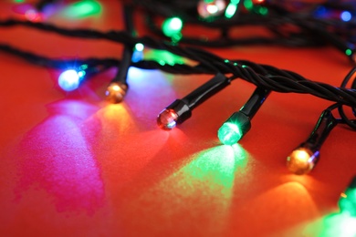 Photo of Glowing Christmas lights on color background, closeup