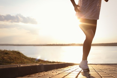 Young woman running near river in morning, closeup. Space for text