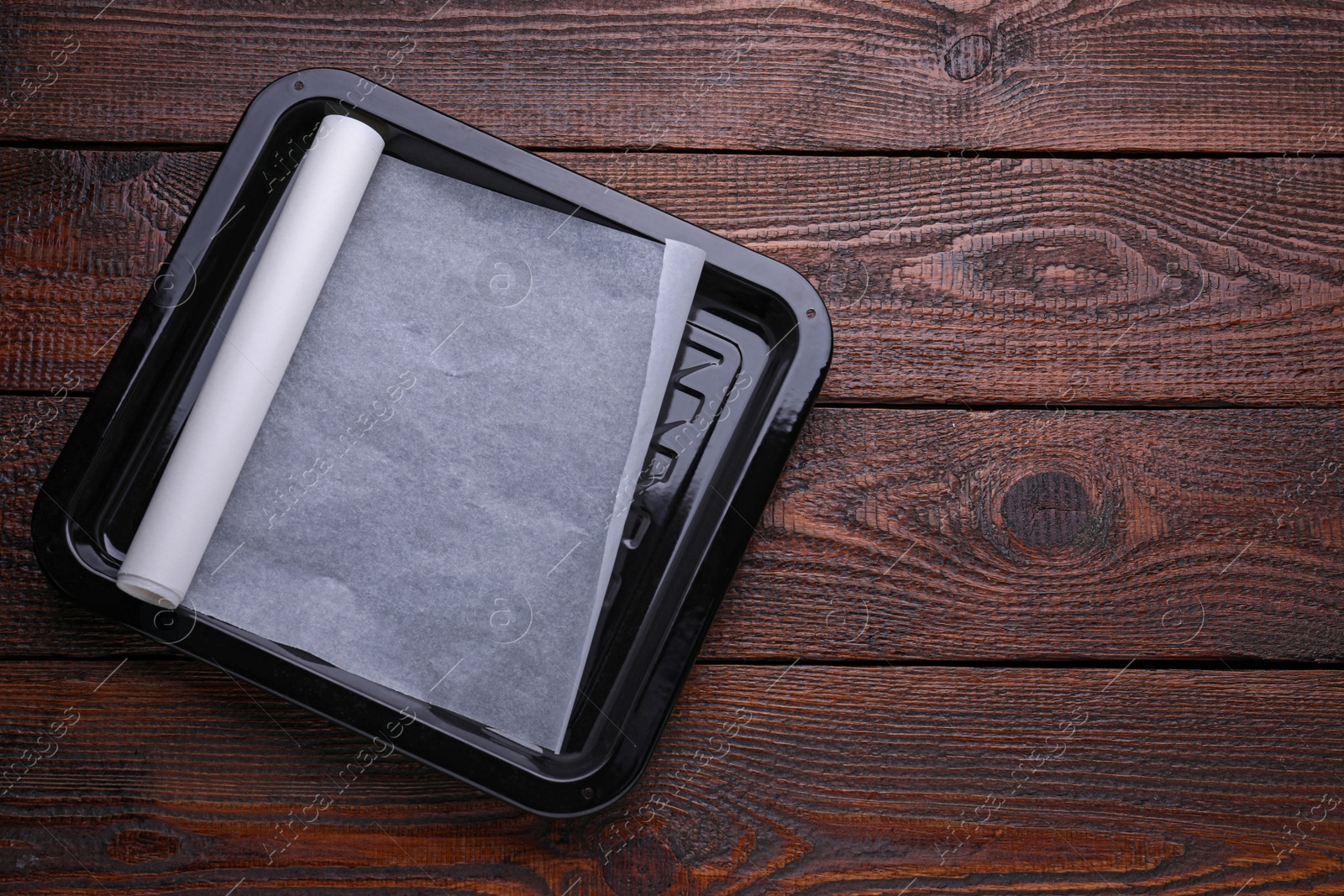 Photo of Baking pan with parchment paper on wooden table, top view. Space for text