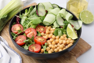 Tasty salad with chickpeas, cherry tomatoes and cucumbers on white table, closeup