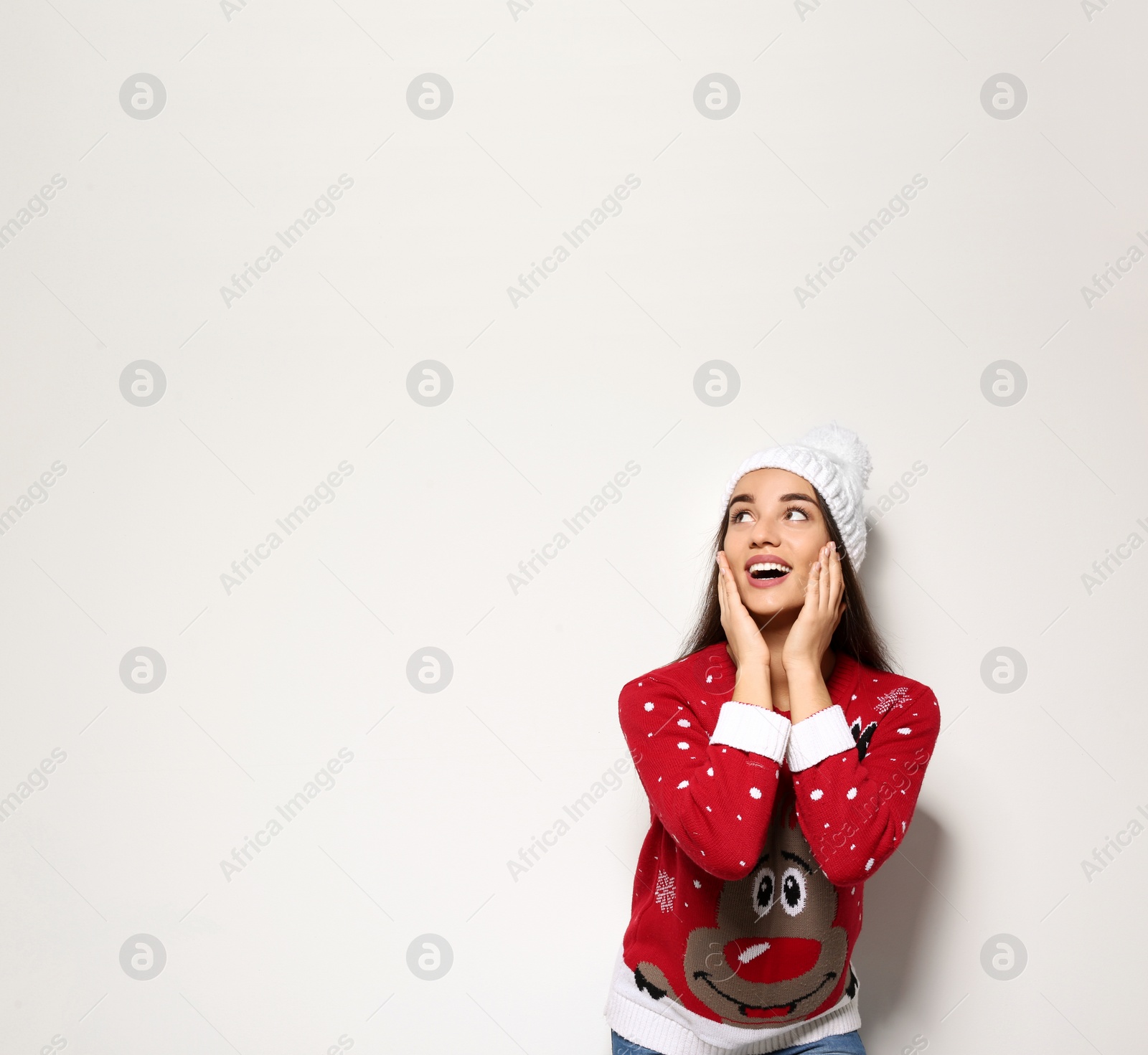 Photo of Young woman in Christmas sweater and knitted hat on white background. Space for text