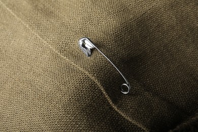 Photo of Metal safety pin on fabric, closeup view