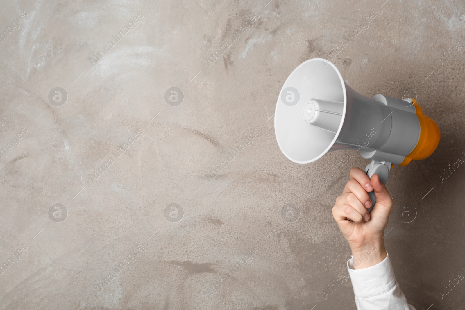 Photo of Woman holding megaphone near color wall