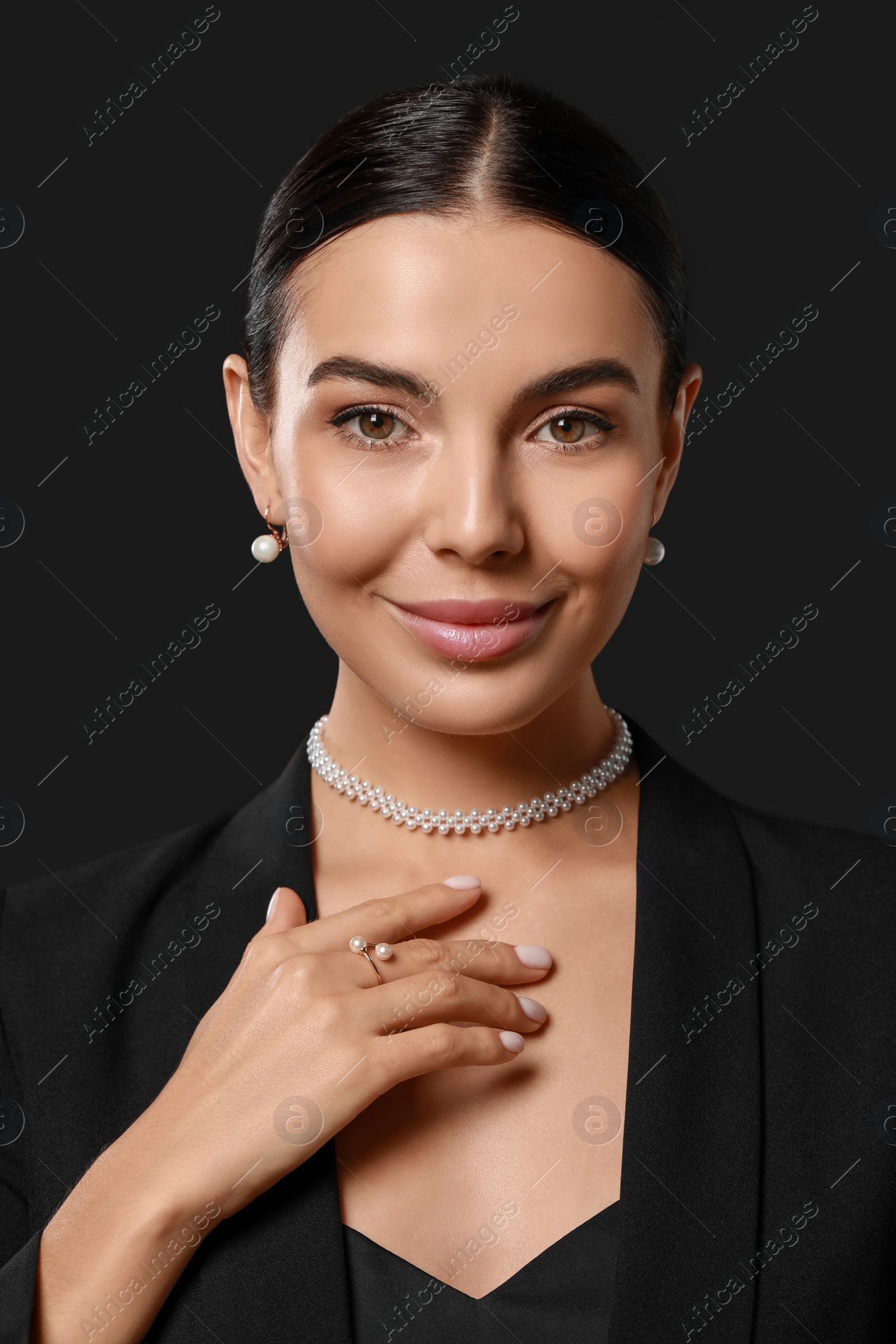 Photo of Young woman with elegant pearl jewelry on black background