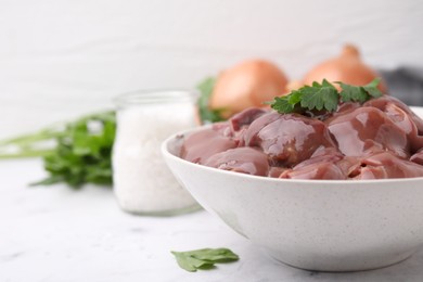 Photo of Bowl of raw chicken liver with parsley on white table, space for text