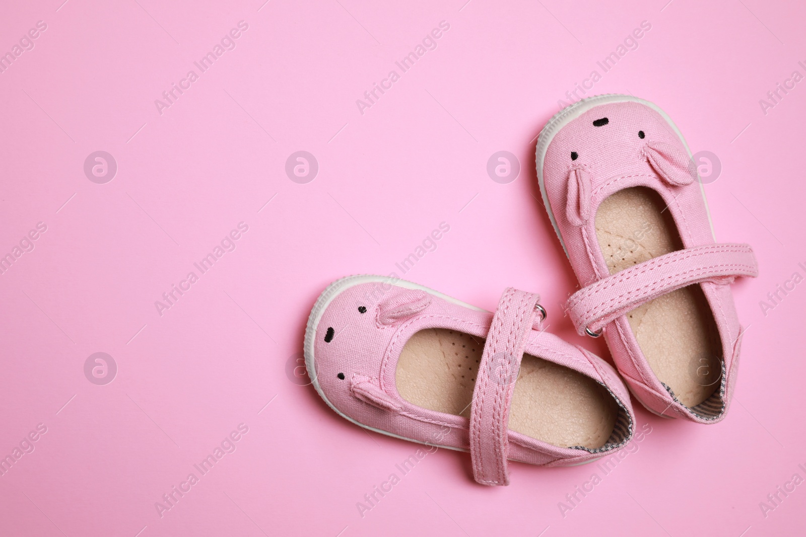 Photo of Cute baby shoes on pink background, flat lay. Space for text