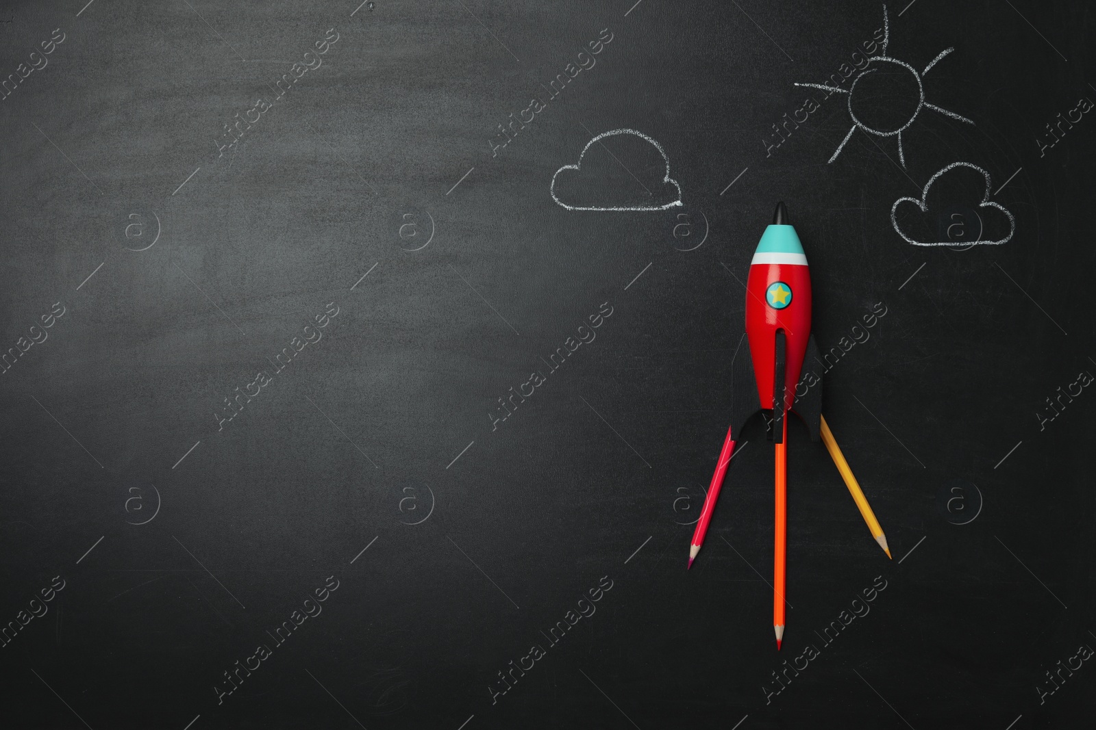 Photo of Bright toy rocket, school supplies and drawings on chalkboard, flat lay. Space for text