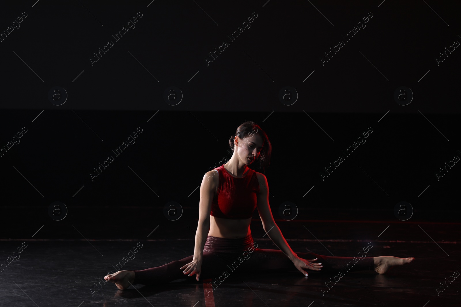 Photo of Young woman performing acrobatic element on stage indoors