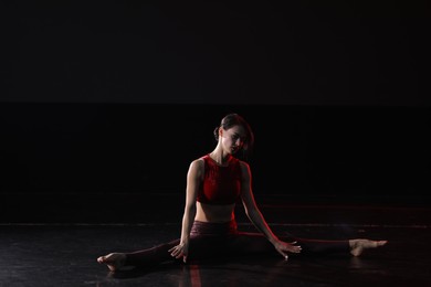 Young woman performing acrobatic element on stage indoors