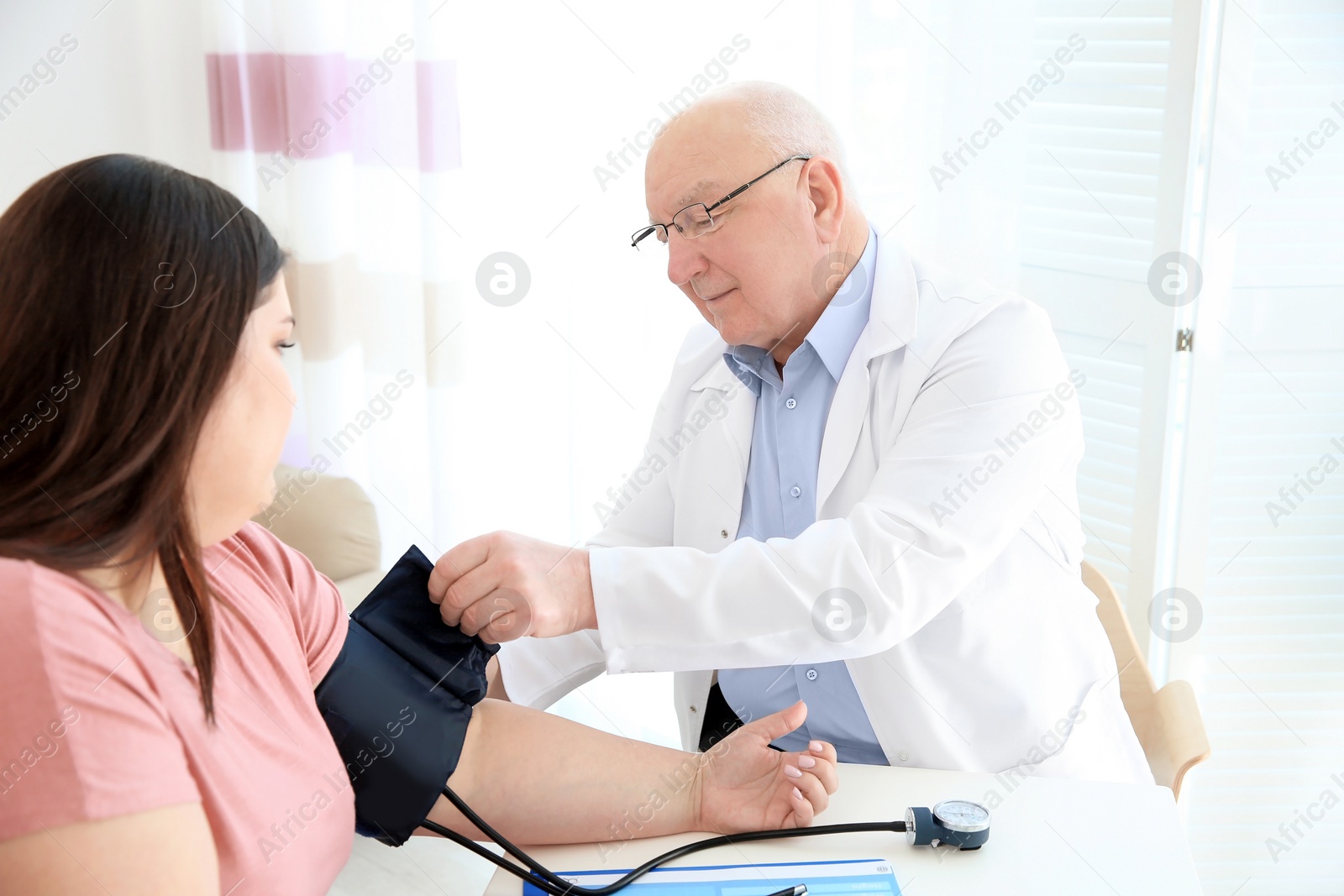 Photo of Doctor measuring blood pressure of overweight woman in clinic