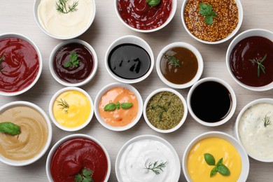 Many bowls with different sauces and herbs on wooden table