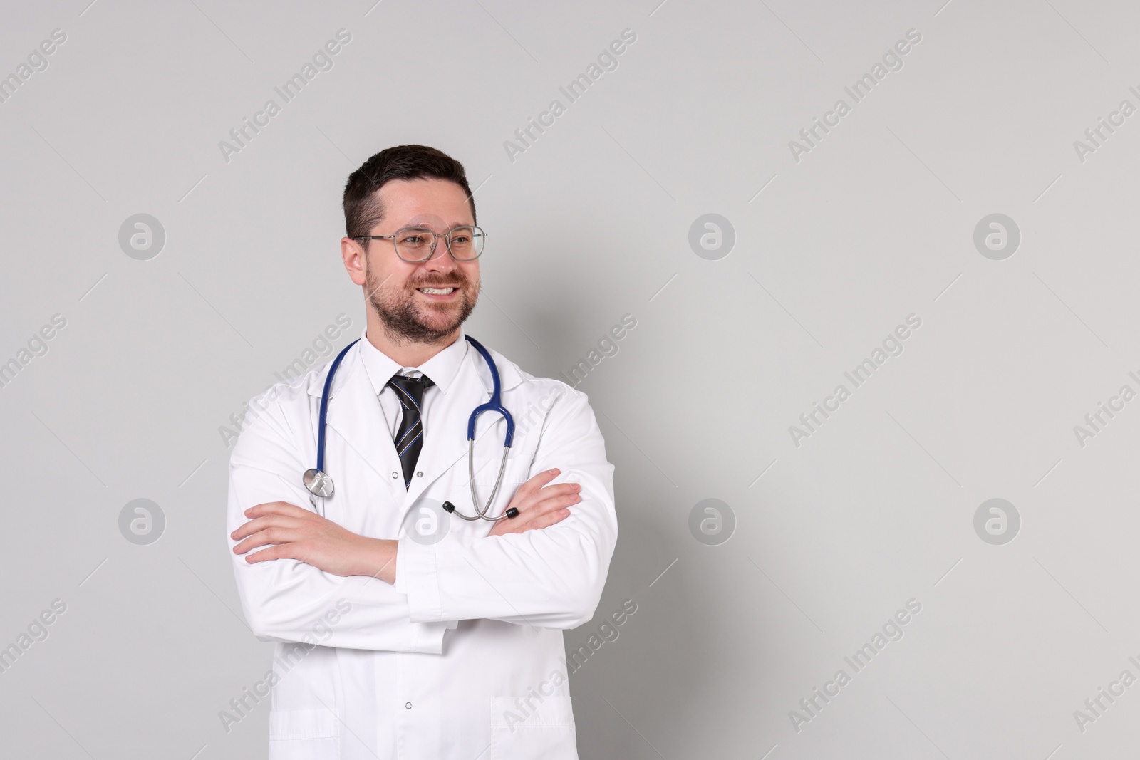 Photo of Portrait of smiling doctor on light grey background, space for text