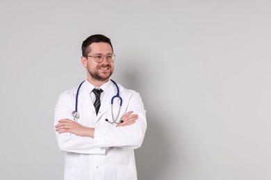 Portrait of smiling doctor on light grey background, space for text