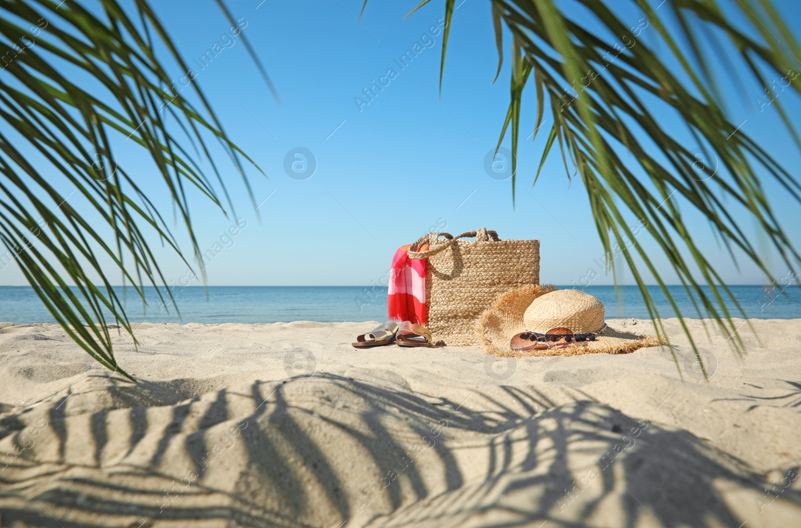 Photo of Stylish beach accessories on sandy sea shore