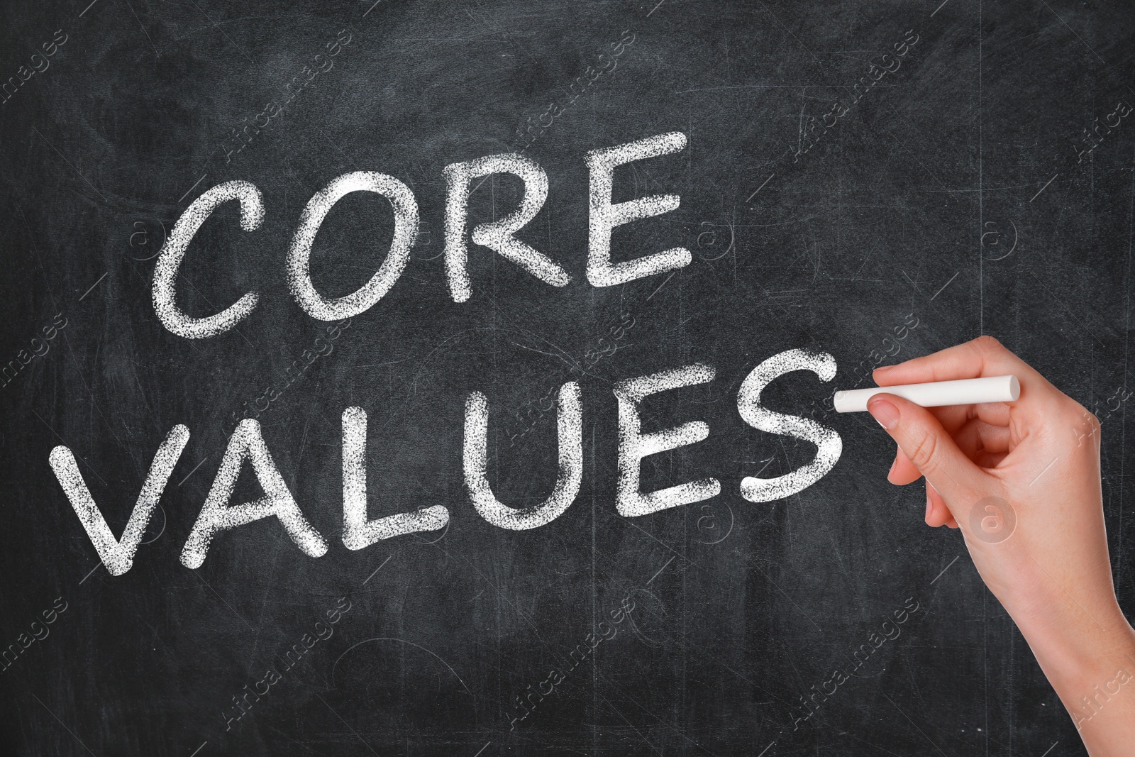 Image of Woman writing phrase CORE VALUES on blackboard, closeup