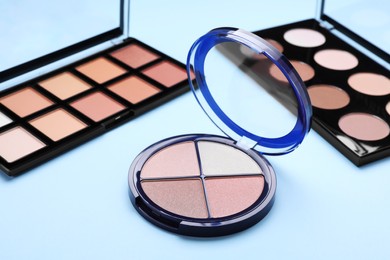 Photo of Different contouring palettes on light blue background. Professional cosmetic product