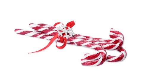 Photo of Sweet Christmas candy canes with red bow and snowflake on white background