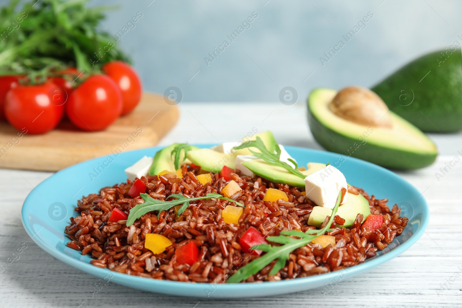 Photo of Plate with delicious cooked brown rice on white wooden table