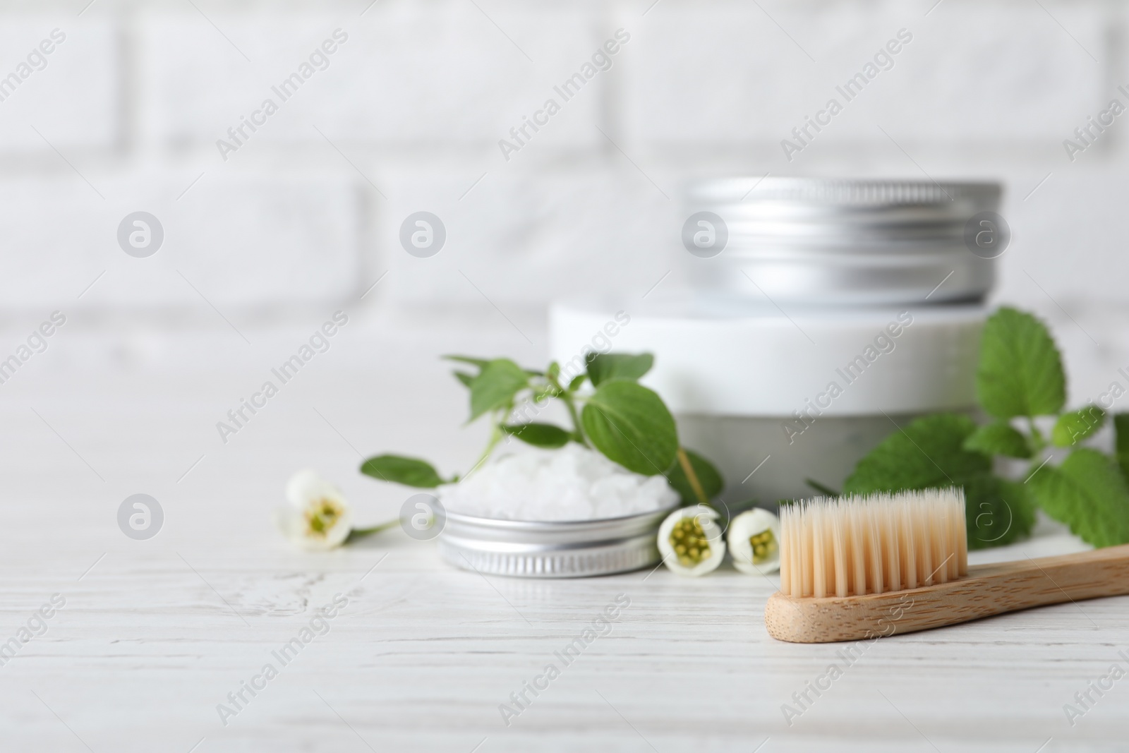 Photo of Toothbrush, dental products and herbs on white wooden table, closeup. Space for text