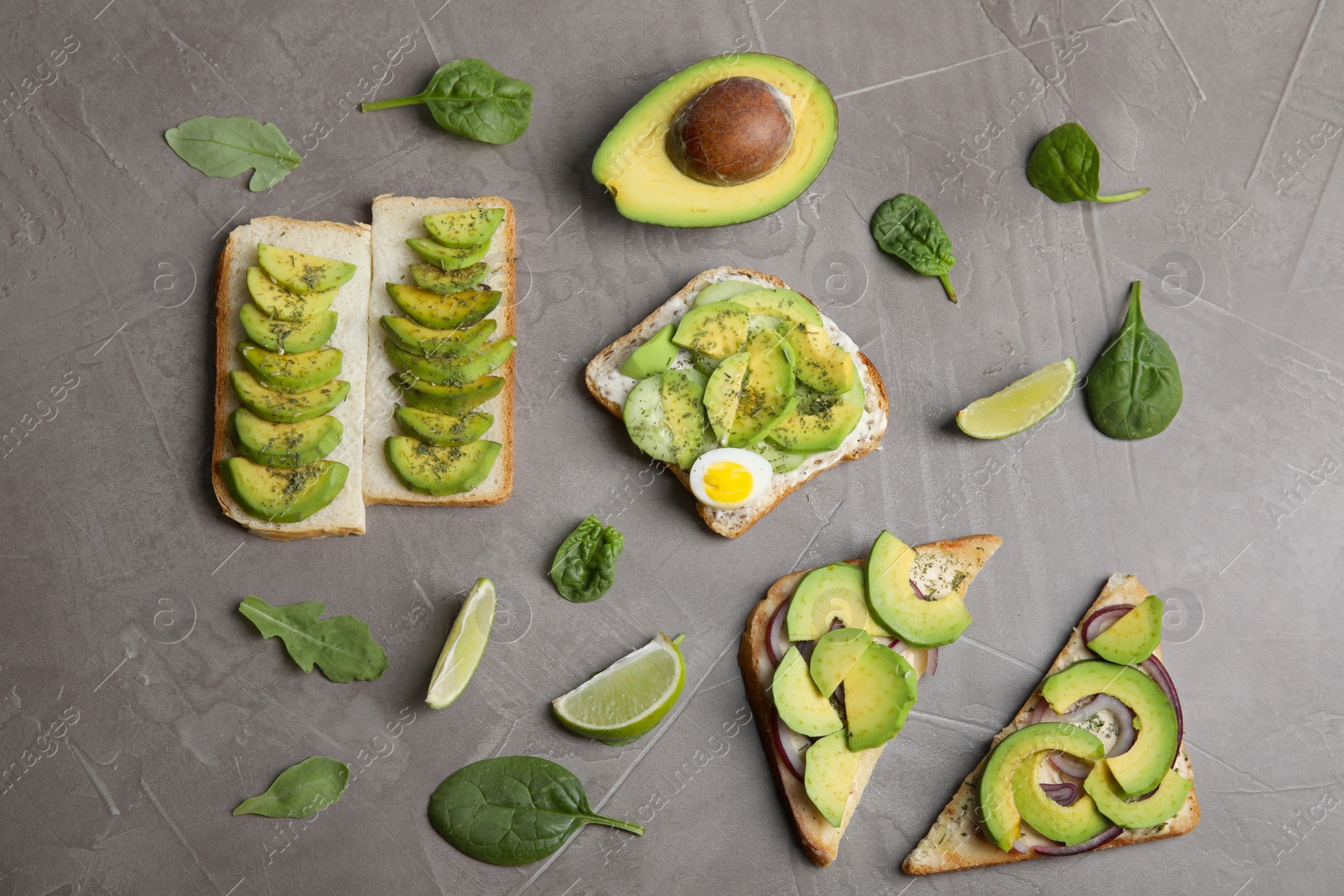 Photo of Flat lay composition with avocado toasts on grey table