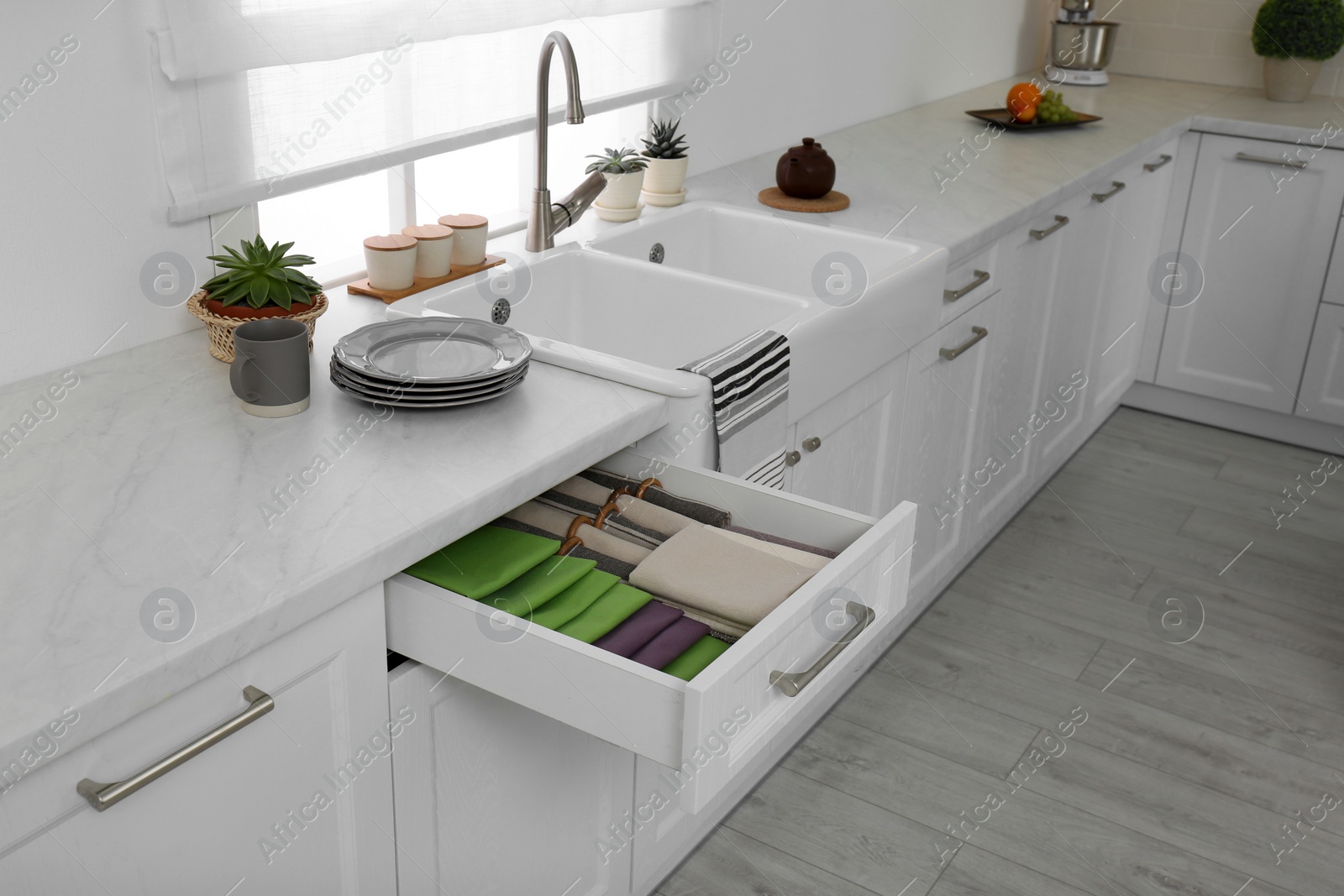 Photo of Open drawer with different folded towels and napkins in kitchen