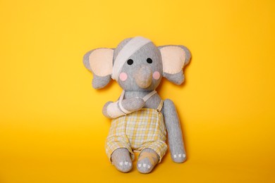 Photo of Toy elephant with bandages on yellow background
