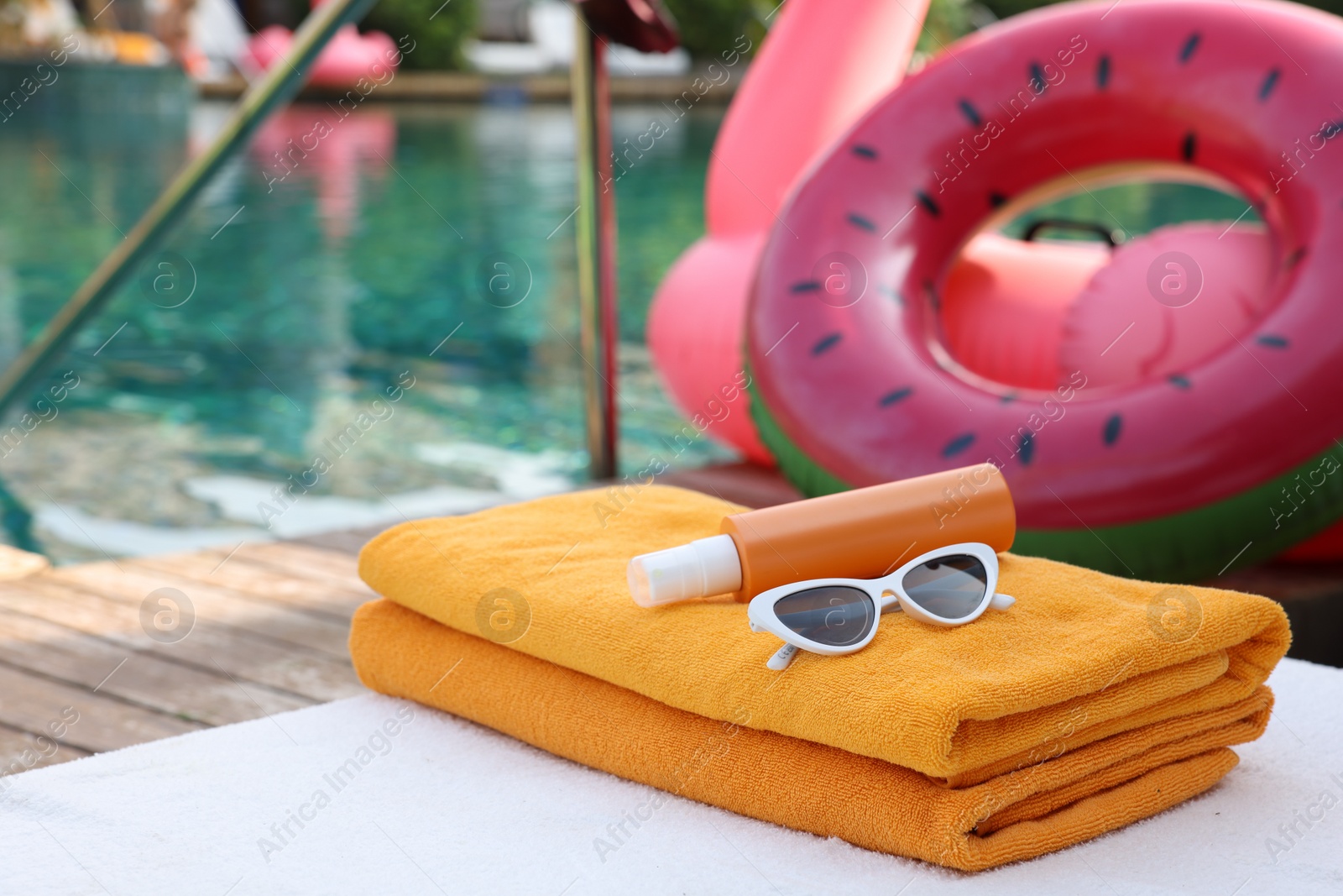 Photo of Beach accessories on sun lounger, inflatable ring and float near outdoor swimming pool. Luxury resort