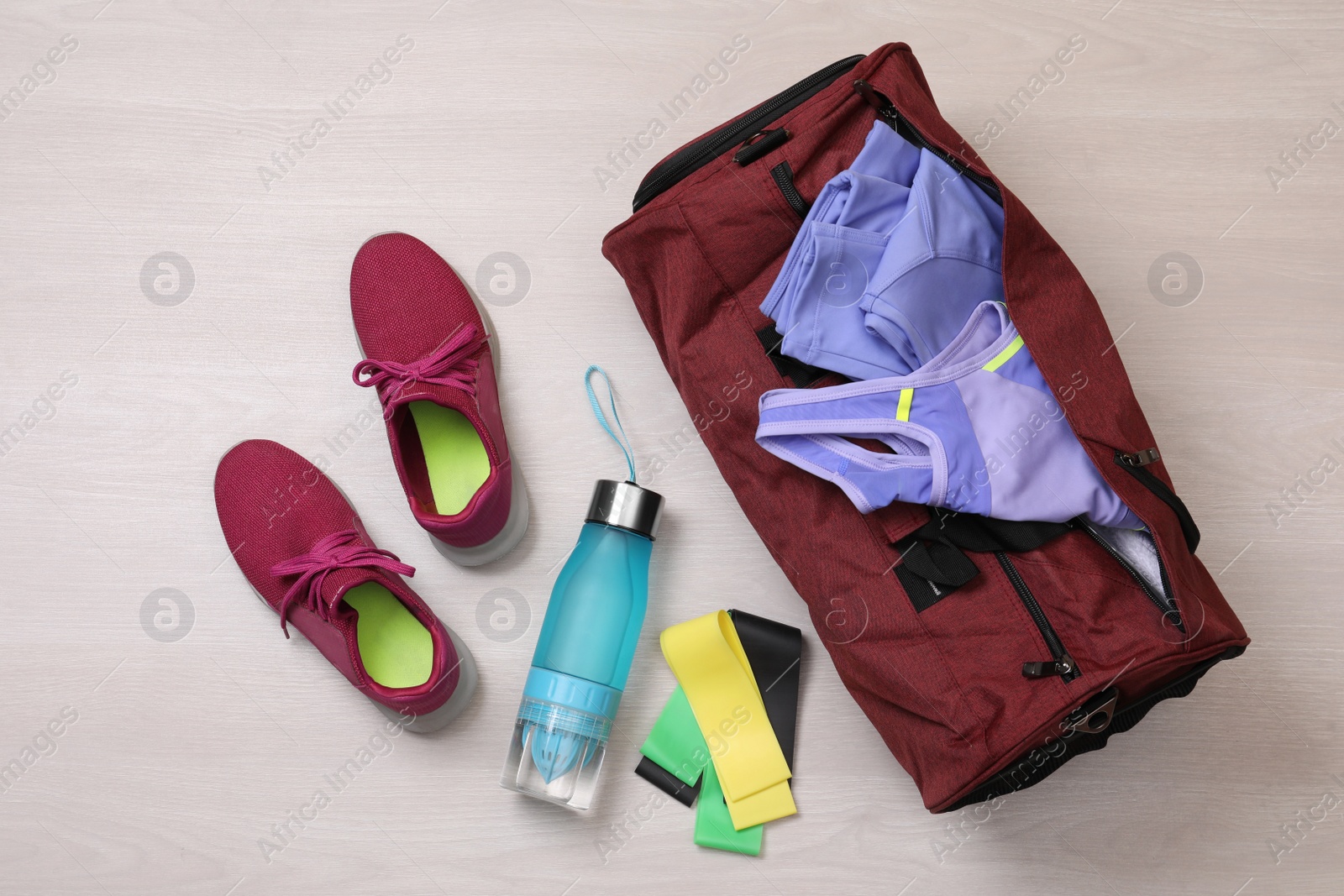 Photo of Gym bag and sports equipment on wooden background, flat lay