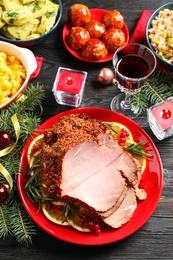 Plate with delicious ham served on dark wooden table, flat lay. Christmas dinner