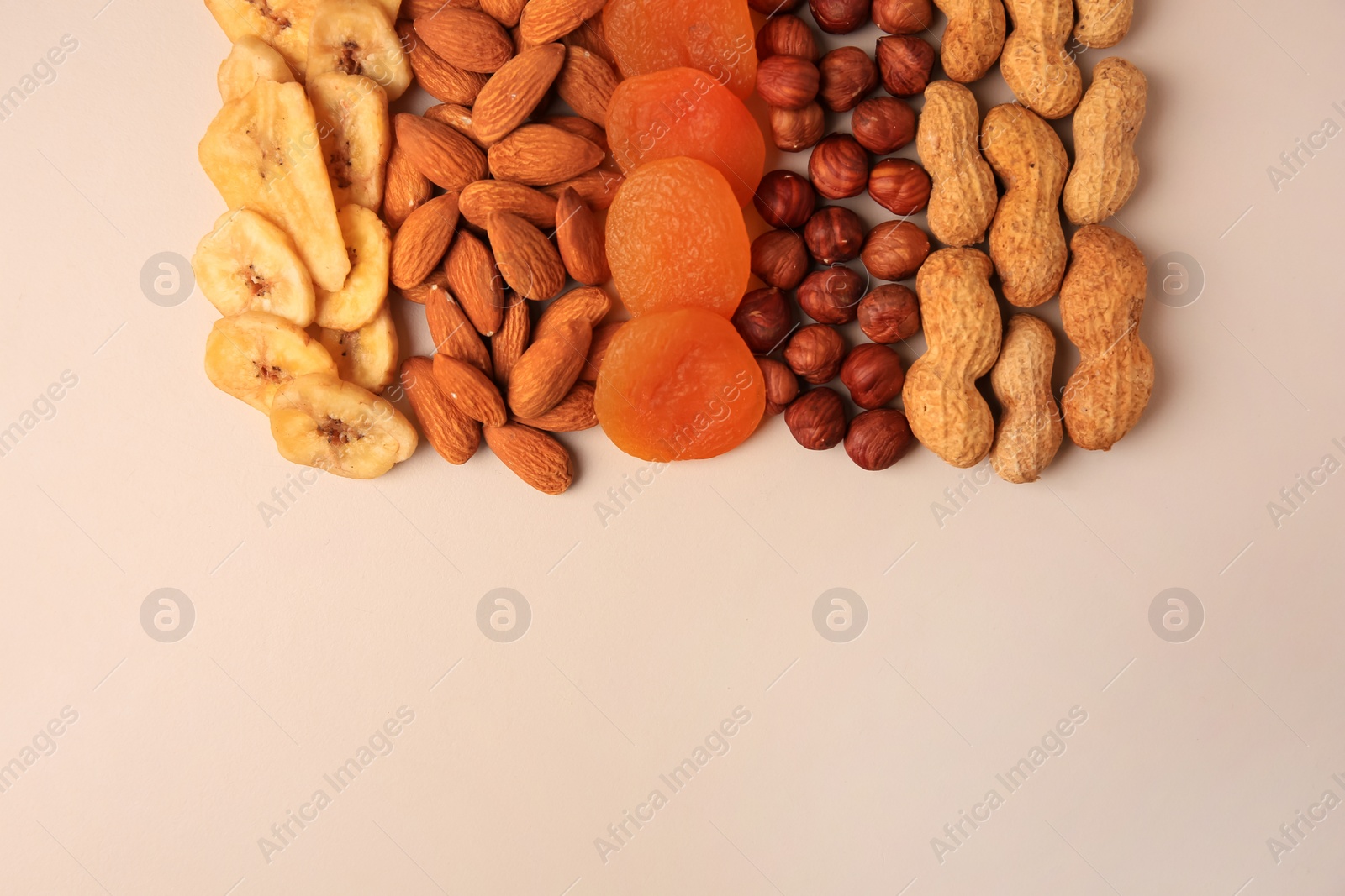 Photo of Mix of delicious dried nuts and fruits on beige background, flat lay. Space for text