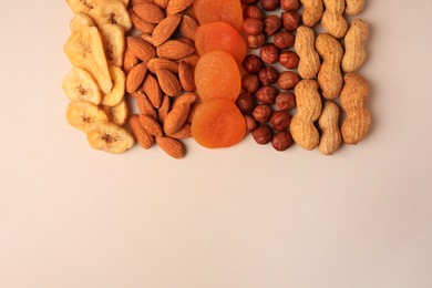 Mix of delicious dried nuts and fruits on beige background, flat lay. Space for text