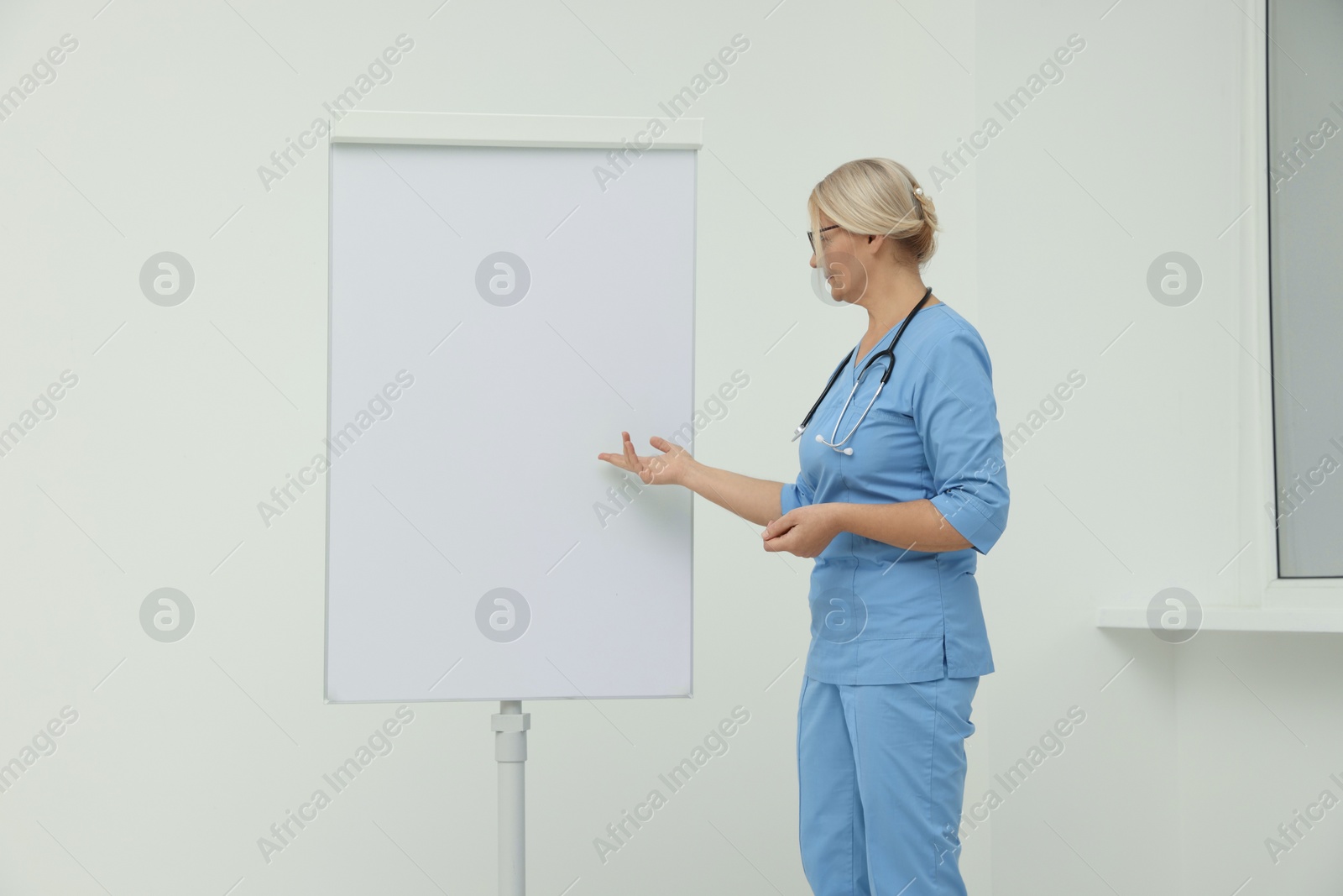 Photo of Professional doctor explaining something near flipchart indoors