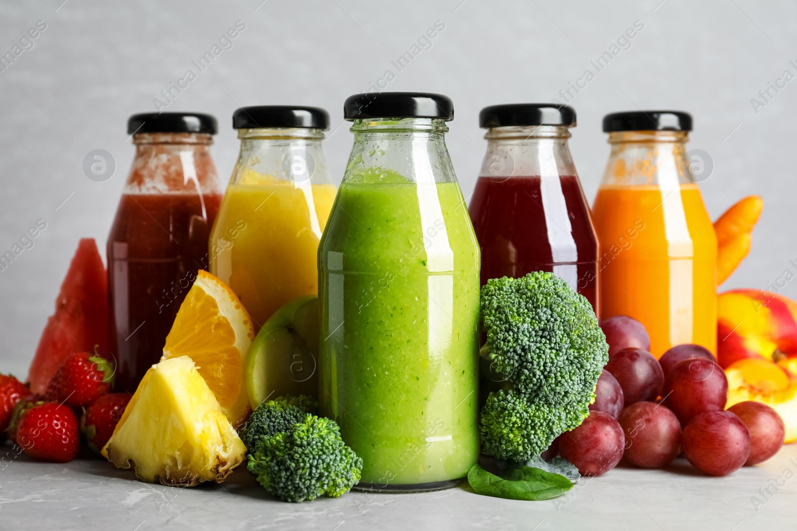 Photo of Bottles of delicious juices and fresh fruits on marble table
