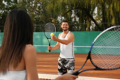 Photo of Happy couple playing tennis on court outdoors