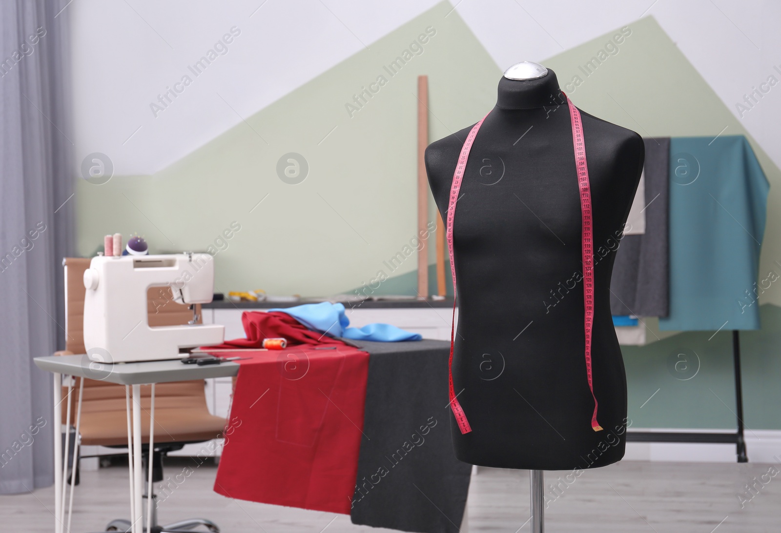 Photo of Tailor workshop interior with mannequin and sewing machine on table