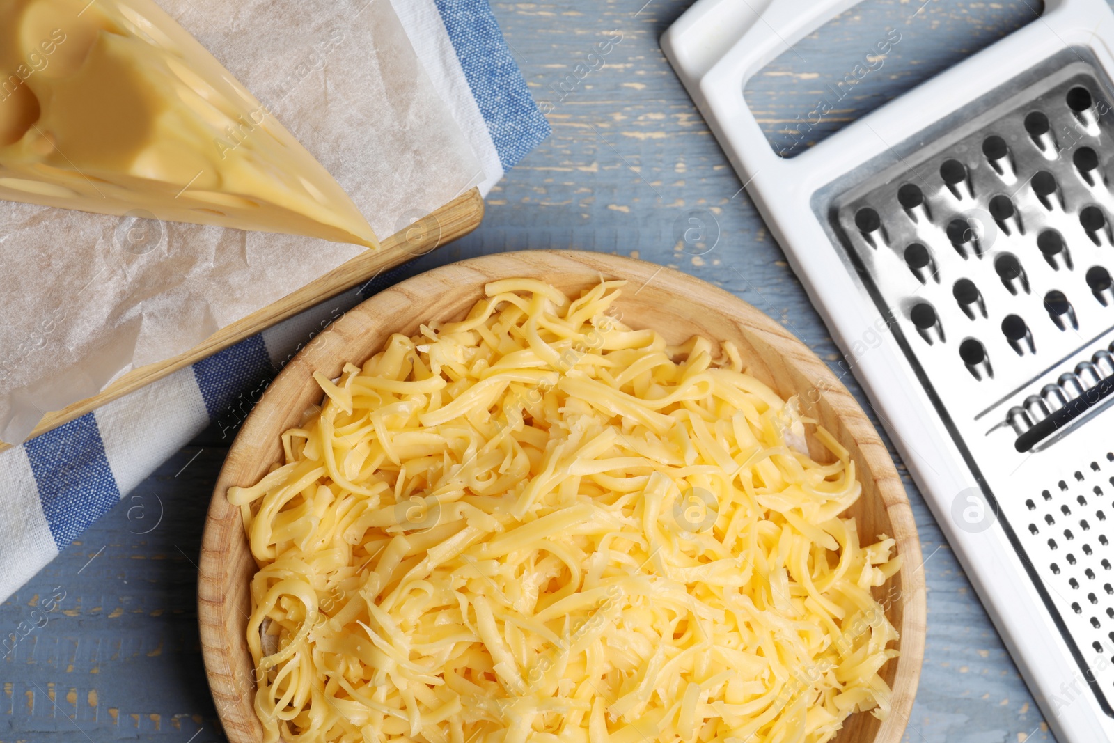 Photo of Tasty grated cheese on light grey wooden table, flat lay