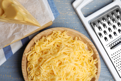 Photo of Tasty grated cheese on light grey wooden table, flat lay