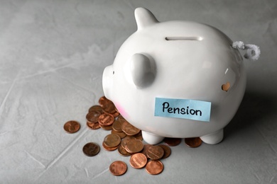 Photo of Piggy bank with word PENSION and coins on table