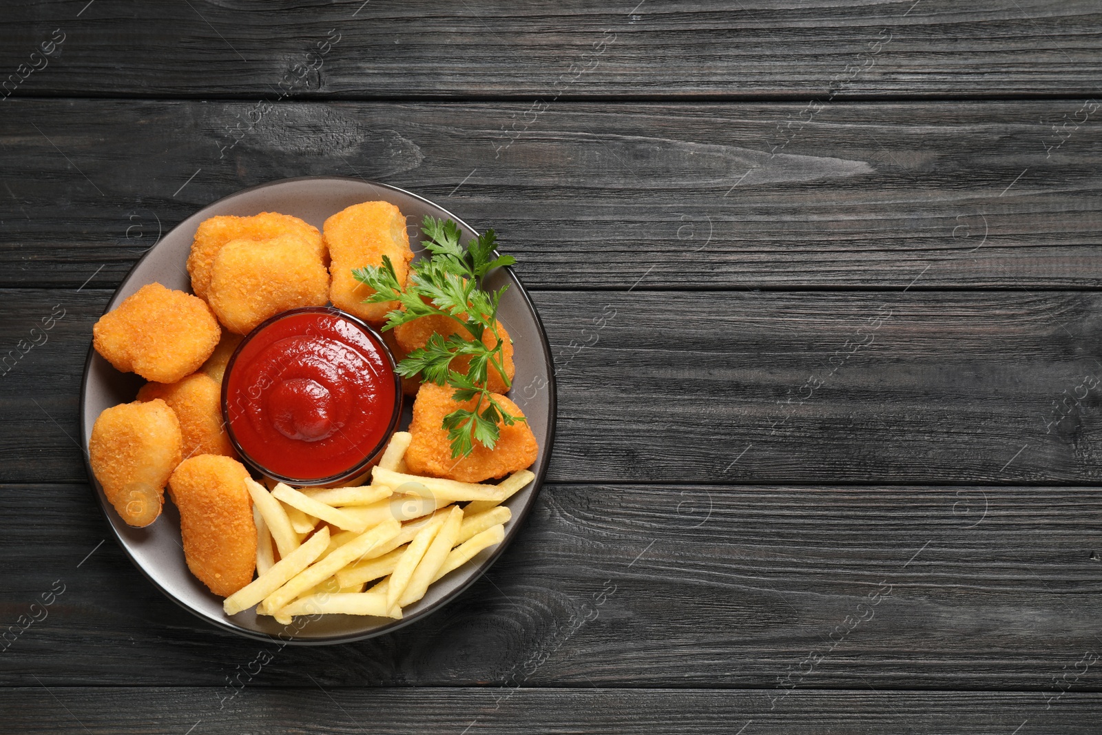 Photo of Tasty fried chicken nuggets with garnish on wooden table, top view. Space for text