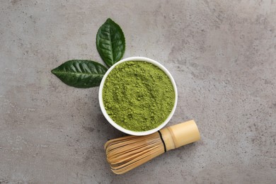 Photo of Green matcha powder, bamboo whisk and leaves on light grey table, flat lay