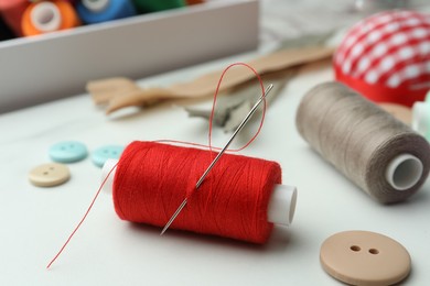 Photo of Threads and other sewing supplies on white marble table