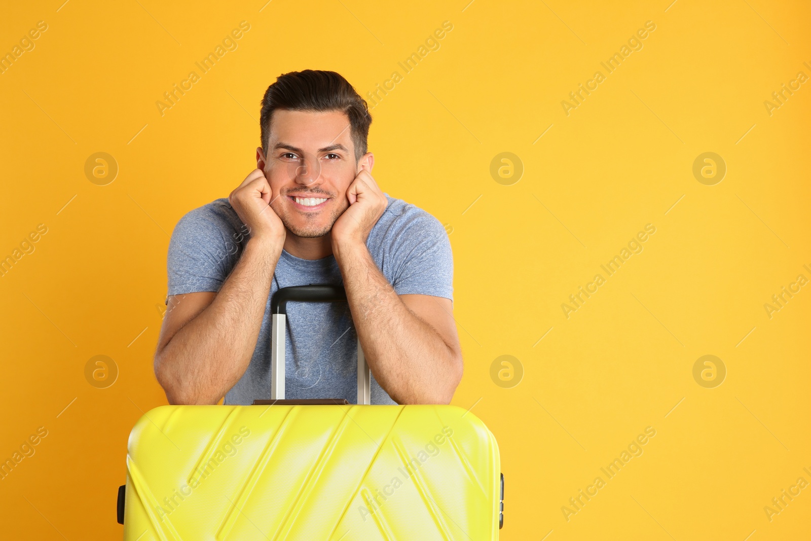 Photo of Handsome man with suitcase for summer trip on yellow background. Vacation travel