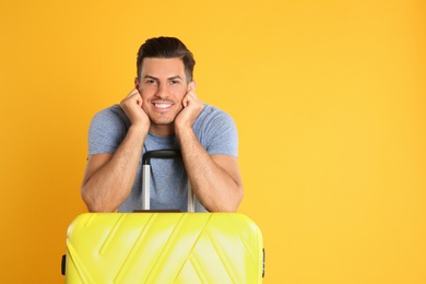 Photo of Handsome man with suitcase for summer trip on yellow background. Vacation travel