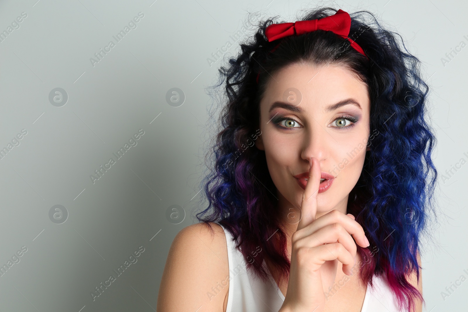 Photo of Emotional young woman with bright dyed hair on grey background