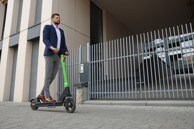 Photo of Businessman riding modern kick scooter on city street, space for text