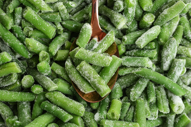 Photo of Frozen green beans and spoon, closeup. Vegetable preservation