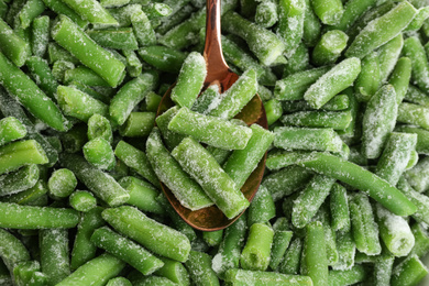 Frozen green beans and spoon, closeup. Vegetable preservation